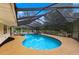 Inviting screened-in pool and spa with a rock feature and a spacious deck surrounded by lush trees at 495 Appaloosa Rd, Tarpon Springs, FL 34688