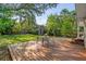 A spacious backyard with a wooden deck and a shed, all surrounded by lush greenery and mature trees at 5707 N Branch Ave, Tampa, FL 33604