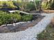 Scenic backyard with a stone pathway leading to a wooden pier, surrounded by lush greenery and water at 6903 11Th Ave E, Palmetto, FL 34221