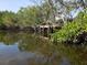 Wooden dock extends over calm, reflective water, surrounded by green foliage at 6903 11Th Ave E, Palmetto, FL 34221