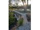 Beautiful landscaping with mature trees, a serene pond, stone steps, and a wooden bridge at 6903 11Th Ave E, Palmetto, FL 34221