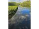 View of lake with green trees and shrubs bordering the pond at 6903 11Th Ave E, Palmetto, FL 34221