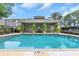 Community pool area with clear blue water, surrounded by lush landscaping and a pool house at 7130 102Nd Ln, Seminole, FL 33772