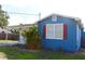 Side view of blue home with a covered carport, lawn, and mature palm tree at 731 20Th Nw St, Largo, FL 33770