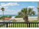 Scenic balcony view overlooking lush green lawn and the Gulf of Mexico beyond the sandy beach at 7564 Bayshore Dr # 302, Treasure Island, FL 33706