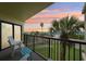 Relaxing balcony view with chairs and table overlooking the beach and vibrant sunset at 7564 Bayshore Dr # 302, Treasure Island, FL 33706