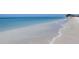 Serene beach with clear, shallow water meeting the soft, white sandy shore at 7564 Bayshore Dr # 302, Treasure Island, FL 33706