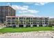 Multi-story condominium building with tiled roofs, balconies, palm trees, and well-maintained grassy areas at 7564 Bayshore Dr # 302, Treasure Island, FL 33706
