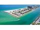 Aerial view of waterfront condos, marina, and stunning turquoise waters on a sunny day in Treasure Island at 7564 Bayshore Dr # 302, Treasure Island, FL 33706
