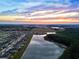 Breathtaking aerial view of a community nestled alongside a scenic lake at sunset at 7819 Notched Pine Bnd, Wesley Chapel, FL 33545