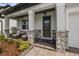 Inviting covered porch featuring stone detailing and comfortable seating area at 7819 Notched Pine Bnd, Wesley Chapel, FL 33545