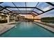 Beautiful screened-in pool area with spa overlooking a tranquil lake at sunset at 7819 Notched Pine Bnd, Wesley Chapel, FL 33545