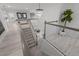 Elegant staircase with a modern chandelier and open landing offers a bright, welcoming transition between floors at 7819 Notched Pine Bnd, Wesley Chapel, FL 33545