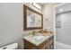 Elegant bathroom featuring a granite countertop, vanity with rustic-style mirror, and modern lighting at 8006 Tanglewood Ln, Tampa, FL 33615