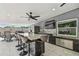Covered outdoor kitchen features stone counter, stainless appliances, a ceiling fan and an outdoor dining space at 8006 Tanglewood Ln, Tampa, FL 33615