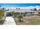Charming single-story home with light blue exterior, a covered carport, and small palm trees in the front yard at 904 Desert Hills Dr, Sun City Center, FL 33573