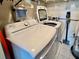 Laundry area with white washing machine and dryer with storage and accessories at 100 Bluff View Dr # 105C, Belleair Bluffs, FL 33770