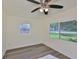 Cozy bedroom with wood flooring, a ceiling fan, and a large window overlooking the yard at 10922 Park Dr, Riverview, FL 33569