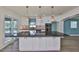 A kitchen features a large island with black countertops, copper pendant lighting, and white cabinetry with stainless steel accents at 10922 Park Dr, Riverview, FL 33569