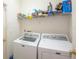 The laundry room has a washing machine and dryer and upper shelving at 11021 Silver Dancer Dr, Riverview, FL 33579