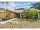 Charming home featuring a stone accent wall, a turquoise front door, and lush landscaping at 11315 N Armenia Ave, Tampa, FL 33612