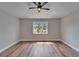 Minimalist bedroom with wood flooring, a ceiling fan, and a view of palm trees outside the window at 12119 Buffington Ln, Riverview, FL 33579