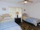 Bright bedroom featuring neutral walls, ceiling fan, and twin beds with matching nightstand at 124 Woodlake Wynde, Oldsmar, FL 34677