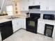 Well-lit kitchen featuring white cabinets, black appliances, and neutral tile flooring at 124 Woodlake Wynde, Oldsmar, FL 34677