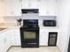 Well-lit kitchen featuring white cabinets, black appliances including a stove, microwave, and wine cooler at 124 Woodlake Wynde, Oldsmar, FL 34677