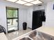 Bright kitchen with white cabinets and black appliances, and a sliding glass door to the outside at 124 Woodlake Wynde, Oldsmar, FL 34677