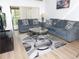 Comfortable living room with a modern sofa, glass coffee table, and sliding glass doors to a patio at 124 Woodlake Wynde, Oldsmar, FL 34677