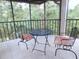 Relaxing screened lanai with a metal table and chairs overlooking mature landscaping at 124 Woodlake Wynde, Oldsmar, FL 34677