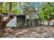 Home's rear exterior featuring a screened-in porch and a yard with mature shade trees at 1332 Marjohn Ave, Clearwater, FL 33756