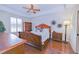 Bedroom with hardwood floors, tray ceiling, ceiling fan, and decorative wall art at 13338 Jaudon Ranch Rd, Dover, FL 33527