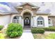 Elegant home entrance with stone accents, arched windows, and lush landscaping at 13338 Jaudon Ranch Rd, Dover, FL 33527