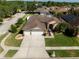 A lovely aerial view of this home featuring a large driveway, a three car garage, solar panels and mature landscaping at 1447 Stetson Dr, Wesley Chapel, FL 33543