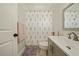 Bright bathroom with a floral shower curtain, grey vanity, and patterned tile flooring at 1447 Stetson Dr, Wesley Chapel, FL 33543