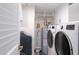 Bright laundry room with modern washer, dryer, water softener, and storage shelves, all efficiently organized at 1600 Gulf Blvd # 1112, Clearwater Beach, FL 33767