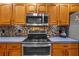 Close up of traditional style kitchen featuring wooden cabinets, stainless steel microwave and range at 18631 Le Dauphine Pl, Lutz, FL 33558