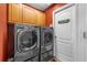 Laundry room with modern washer and dryer, upper cabinets, and adjacent exterior door at 18631 Le Dauphine Pl, Lutz, FL 33558