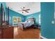 Serene main bedroom with blue walls, wood floors, and a decorative ceiling fan at 18631 Le Dauphine Pl, Lutz, FL 33558