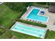 Aerial view of a community pool, a kiddie pool, and a shuffleboard surrounded by lush landscaping at 3010 Beecher E Dr # A, Palm Harbor, FL 34683