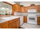 A kitchen features wood cabinets, white appliances, and tile backsplash at 3010 Beecher E Dr # A, Palm Harbor, FL 34683