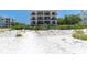 Beachfront building with multiple balconies overlooks a pristine white sand beach with lush vegetation at 3200 Gulf Blvd # 202, St Pete Beach, FL 33706