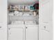 Convenient laundry area with a washer, dryer, and storage shelving at 3200 Gulf Blvd # 202, St Pete Beach, FL 33706
