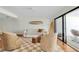 Well-lit living room featuring a surfboard art piece, neutral tones, wood floors, and a glimpse of the ocean view at 3200 Gulf Blvd # 202, St Pete Beach, FL 33706