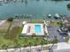 Aerial shot of the community pool, surrounded by lush landscaping, parking, and waterway access at 3200 Gulf Blvd # 202, St Pete Beach, FL 33706
