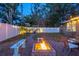 Backyard with a stone fire pit, bench seating, string lights, and a white privacy fence, perfect for outdoor relaxation at 3245 Freemont S Ter, St Petersburg, FL 33712