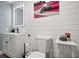 This bathroom features plank walls, a toilet, a modern sink, a mirror with lighting, and a unique artwork at 3245 Freemont S Ter, St Petersburg, FL 33712