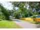 Residential street view featuring tree coverage, landscaping, and a yellow fence at 351 Hancock St, Dunedin, FL 34698